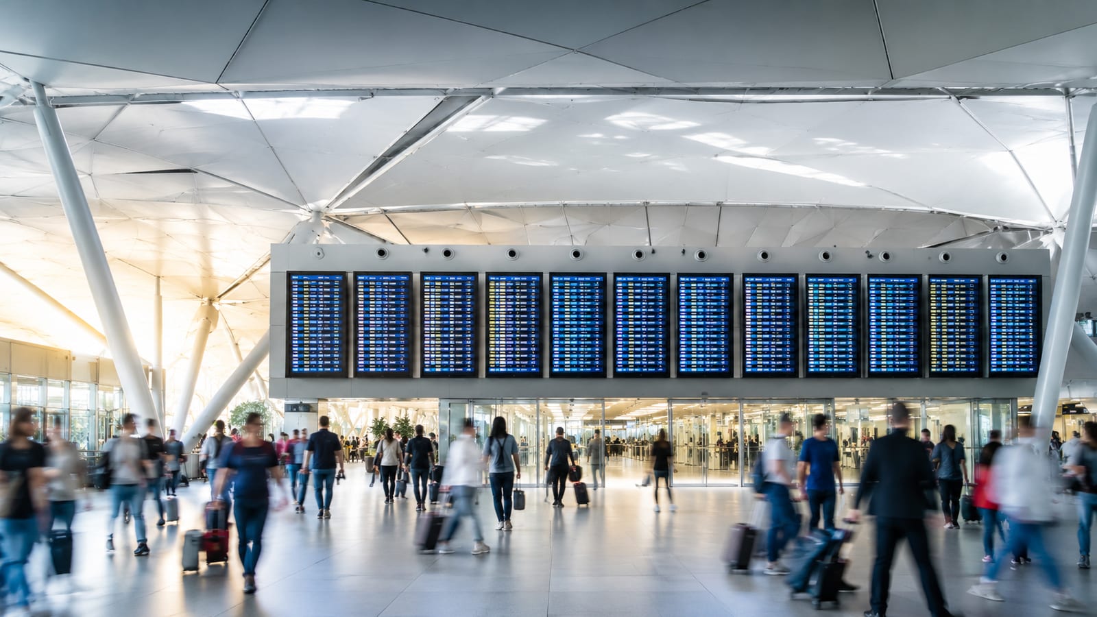 airport departure board with flight information and travelers in terminal