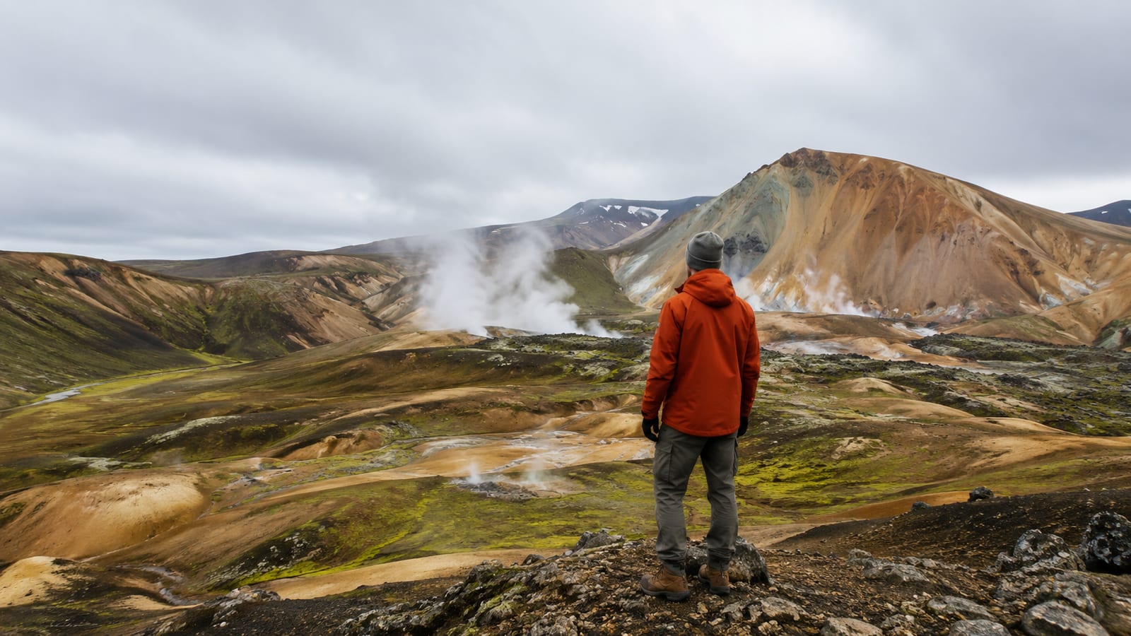 Traveler on Iceland's dramatic volcanic landscape with geothermal features and moss-covered lava fields