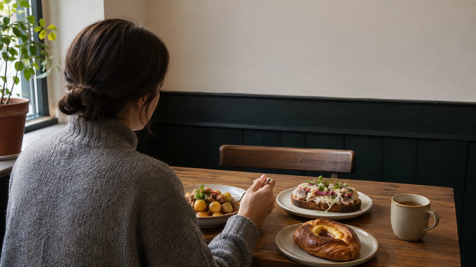 Solo traveler sampling smørrebrød, pastry, and a warm Danish dish at a casual table