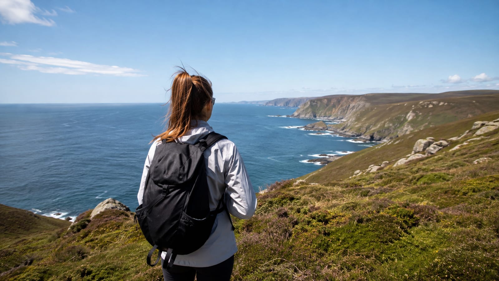 Solo traveler hiking a scenic coastal trail under comfortable spring weather