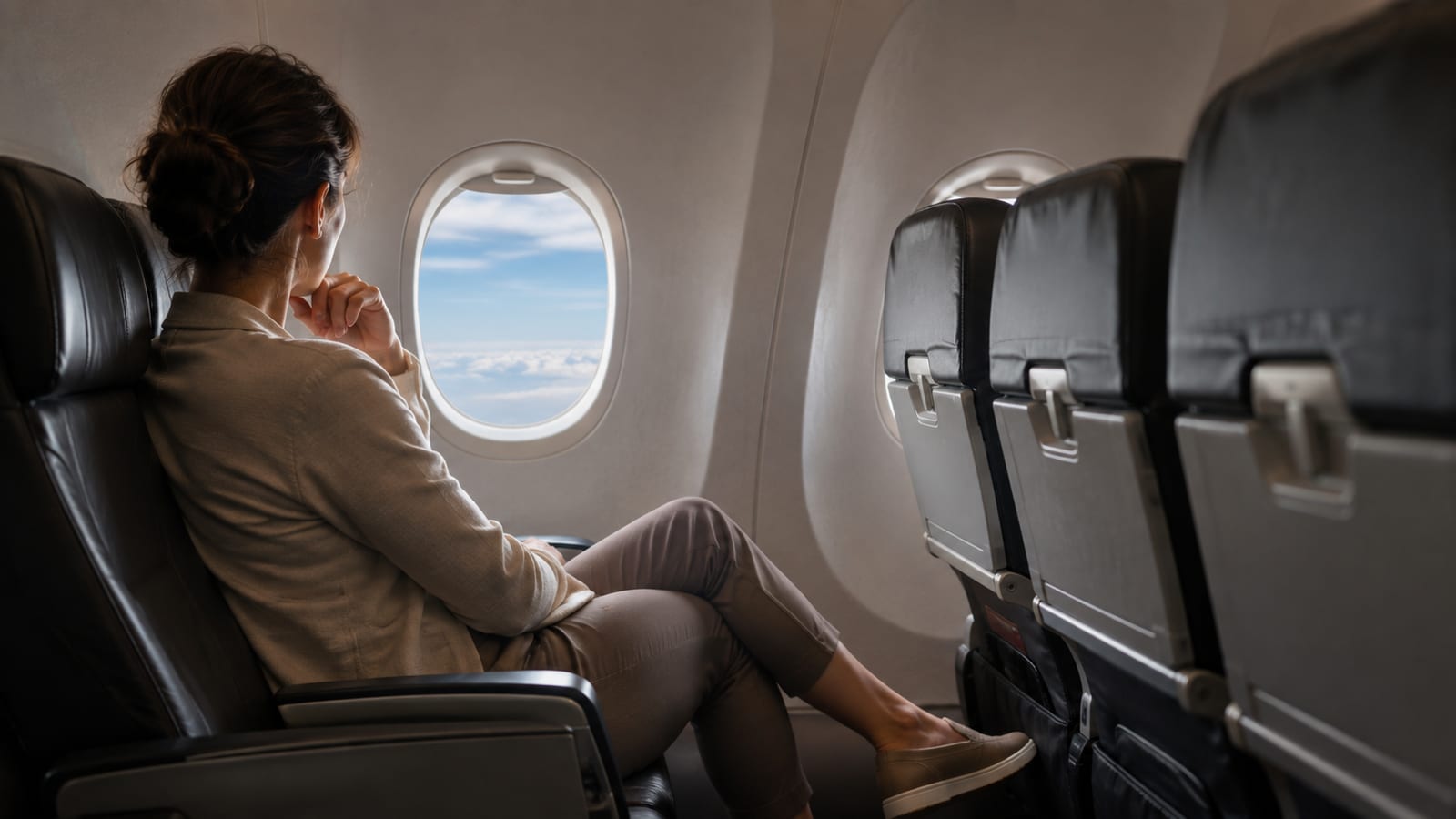 Traveler in polished layered outfit relaxing in a generic airplane cabin overnight