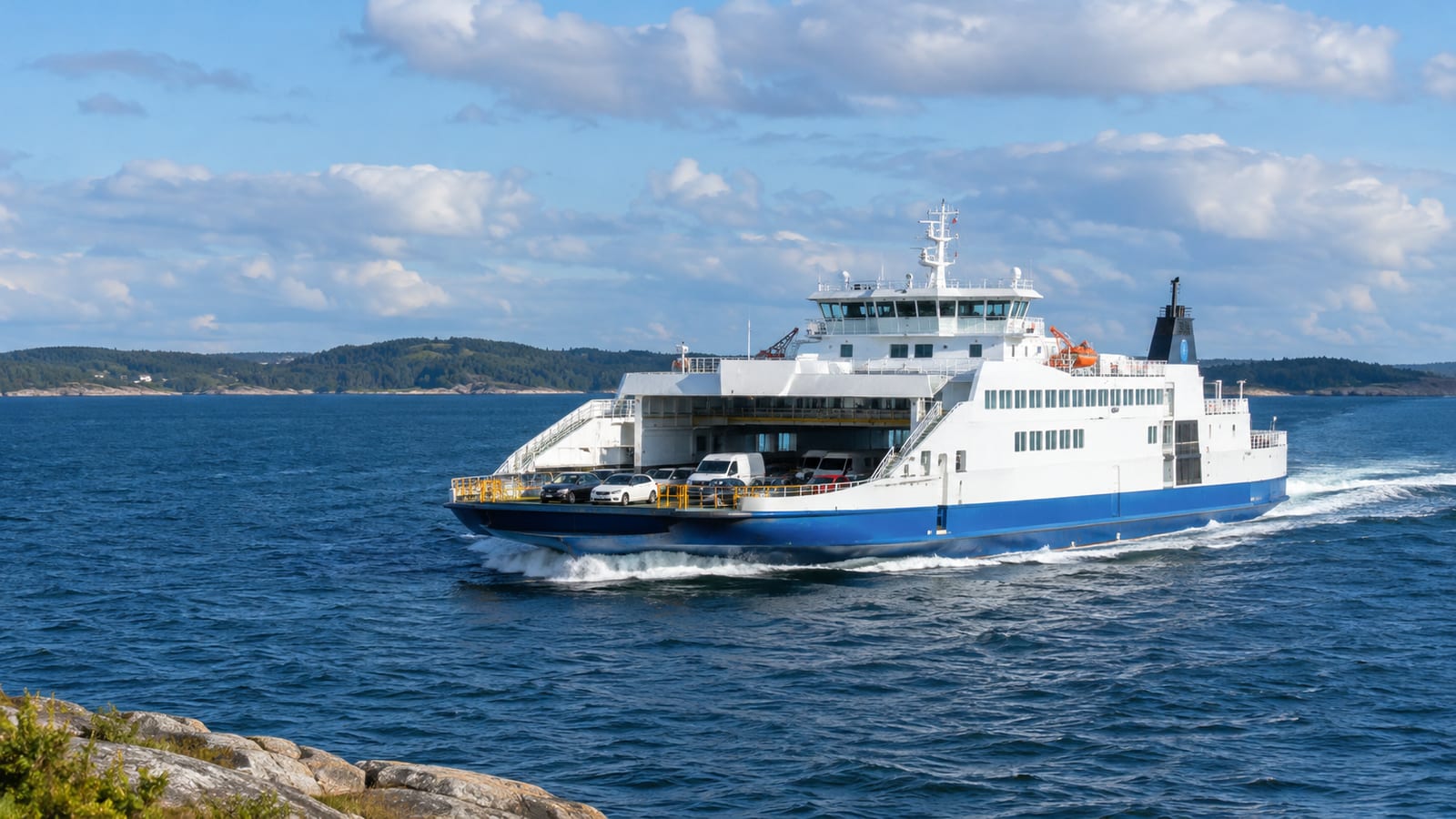 A large blue and white car ferry carrying vehicles cruises across open ocean water
